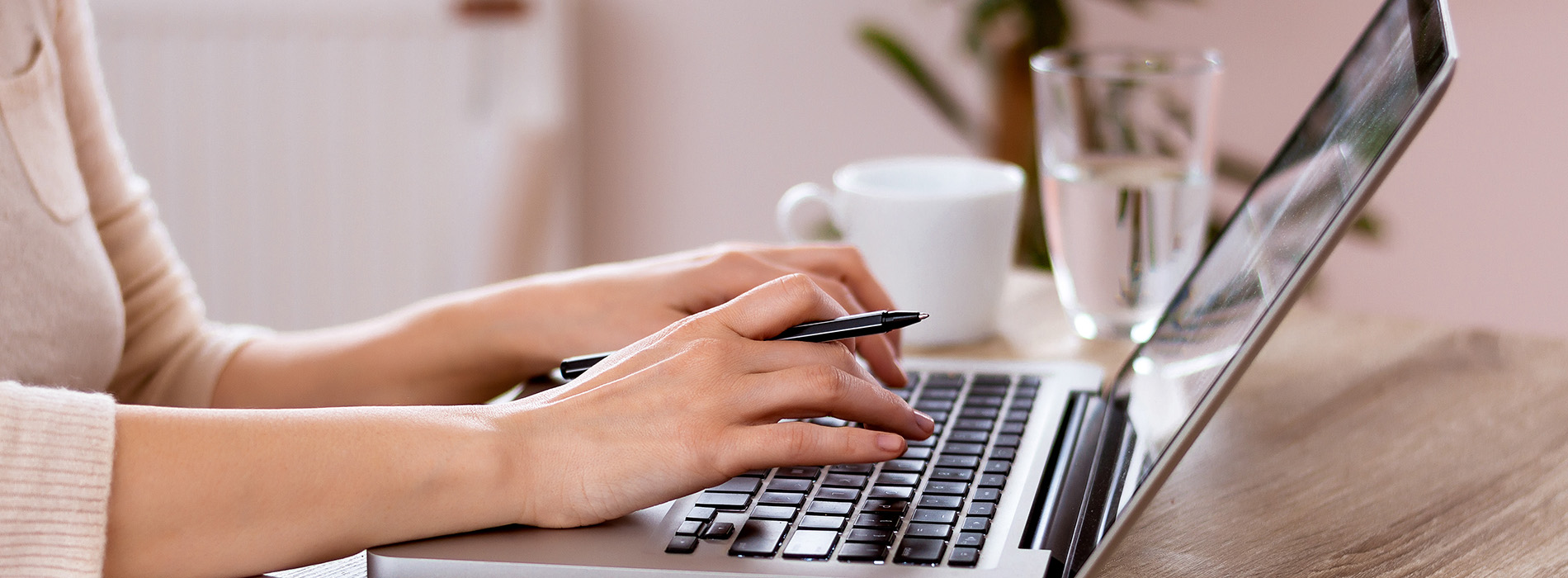 A person typing on a laptop computer with their hands, set against a blurred background.